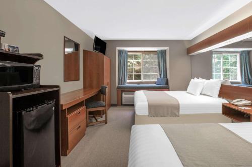 um quarto de hotel com duas camas e uma televisão em Microtel Inn & Suites by Wyndham Gardendale em Gardendale