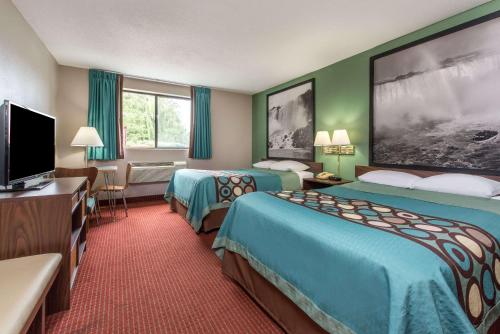 a hotel room with two beds and a flat screen tv at Super 8 by Wyndham Niagara Falls in Niagara Falls