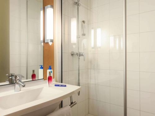 a white bathroom with a shower and a sink at ibis Compiegne in Compiègne