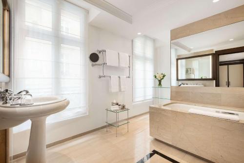 a bathroom with a tub, sink and mirror at Hyatt Paris Madeleine in Paris