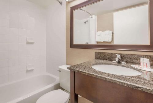 a bathroom with a sink and a toilet and a mirror at Baymont by Wyndham Red Deer in Red Deer