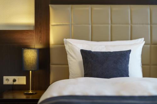 a bed with a blue and white pillow and a lamp at Hotel Continental Hamburg Hauptbahnhof in Hamburg