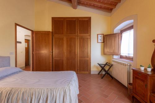 a bedroom with a bed and wooden cabinets and a window at Agriturismo I Bonsi in Reggello