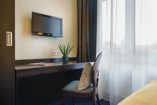 a hotel room with a desk with a tv and a chair at Hotel Continental Hamburg Hauptbahnhof in Hamburg