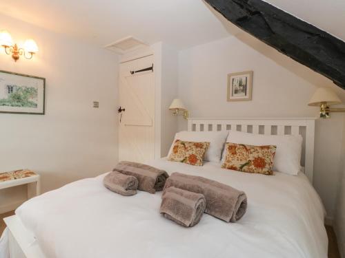 a bedroom with a white bed with two pillows on it at Snowdrop Cottage in Sherborne