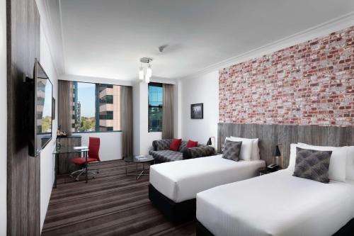 a hotel room with two beds and a brick wall at Rydges Sydney Central in Sydney