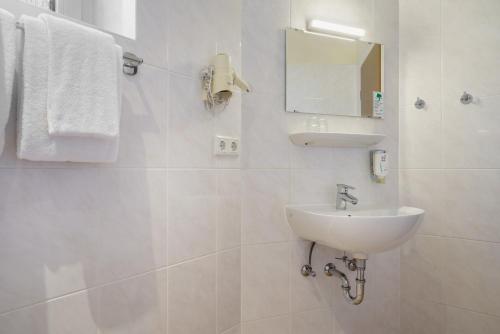 a white bathroom with a sink and a mirror at Hotel Continental Hamburg Hauptbahnhof in Hamburg