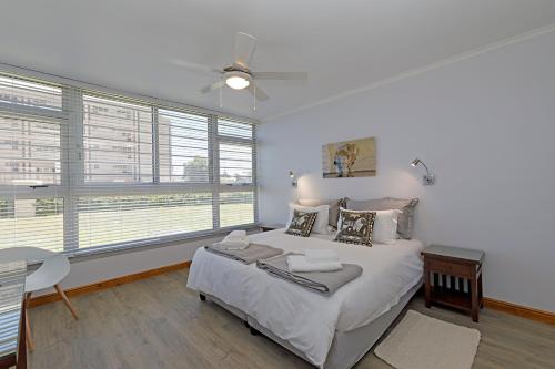 a bedroom with a large bed with a ceiling fan at Ocean-Song in Strand