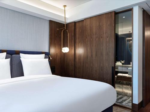 a bedroom with a white bed and a wooden wall at Athens Capital Center Hotel - MGallery Collection in Athens