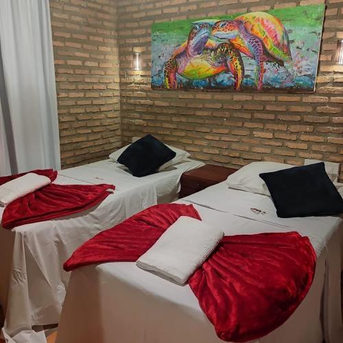 two beds in a room with a painting on the wall at Chalé 17 - Porto do Sol - Pipa in Pipa