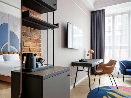 een hotelkamer met een bed, een tafel en een bureau bij Mercure Krakow Fabryczna City in Krakau