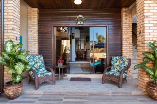 a porch with two wicker chairs and a glass door at Pousada Recanto do Aconchego in Florianópolis
