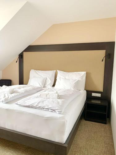 a large bed with white sheets and pillows at Penzion U Broucka in Milevsko