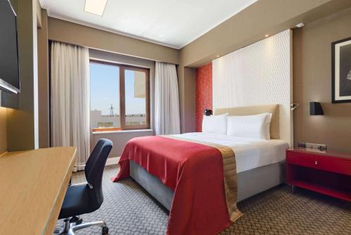 a hotel room with a bed and a desk and a window at Ramada Plaza by Wyndham Eskisehir in Eskisehir