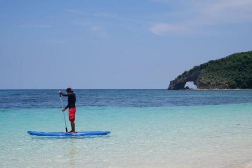 a man standing on a paddle board in the ocean at Belmont Hotel Boracay near Newcoast Beach in Boracay