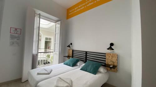 two twin beds in a room with a window at Planeta Cadiz Hostel in Cádiz