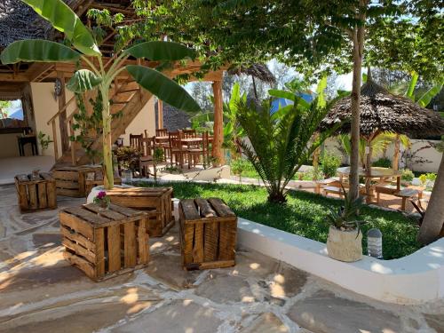 a patio with chairs and tables and trees at Zanzibar Tropical Sunset Boutique Hotel - Adults Only in Kiwengwa