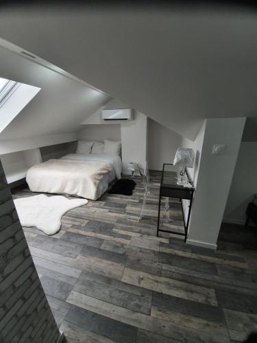 a attic bedroom with a bed and a table at La Bonbonnière by Leslodgespa in Hésingue