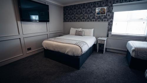 a bedroom with a bed and a tv on the wall at Beechlawn Hotel in Belfast