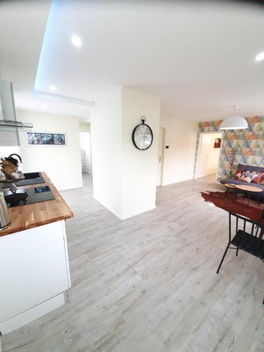 a kitchen and living room with white walls and wooden floors at La Bonbonnière by Leslodgespa in Hésingue