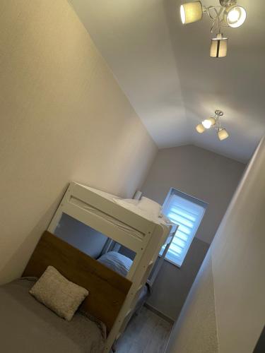 an attic room with a bunk bed and a window at Sirály 2 Apartman in Hajdúnánás