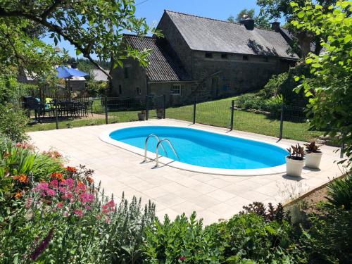 a swimming pool in a yard next to a house at Walnut Tree Gite Brittany in Boderel