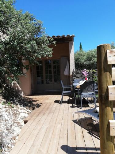 a wooden deck with a table and chairs on it at Les Garrigues de la Vallée des Baux in Paradou