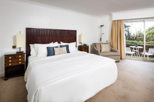 a bedroom with a large white bed and a chair at The Atlantic Hotel - Small Luxury Hotels of the World in St Brelade