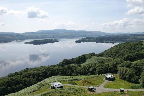 a view of a lake with two huts on a hill at Odhrán Lodge, St Conan's Escape: Home with a view in Loch Awe