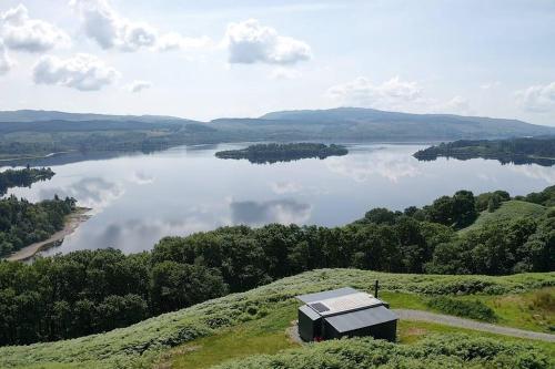 a small building on a hill overlooking a lake at Odhrán Lodge, St Conan's Escape: Home with a view in Loch Awe