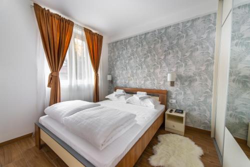 una camera da letto con un letto con lenzuola bianche e una finestra di GreenWood apartments in Kraljevi Cardaci a Kopaonik