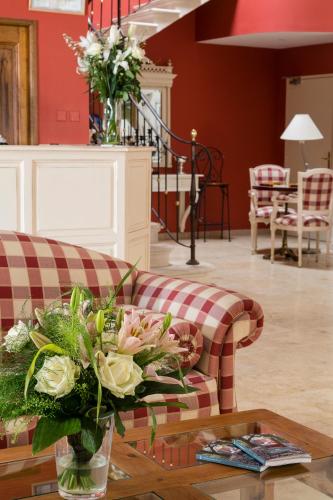 a living room with a couch and a table with flowers at Hotel Restaurant Le Clos De Pradines in Saint-Quentin-la-Poterie