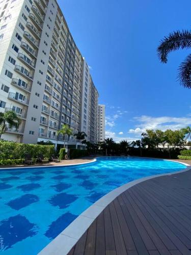 a large blue swimming pool next to a building at Cozy 1 BR Apartment At South Residences Tower 2 in Manila