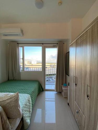 a bedroom with a bed and a large window at Cozy 1 BR Apartment At South Residences Tower 2 in Manila