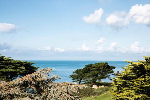 a view of the ocean from a hill with trees at The Atlantic Hotel - Small Luxury Hotels of the World in St Brelade