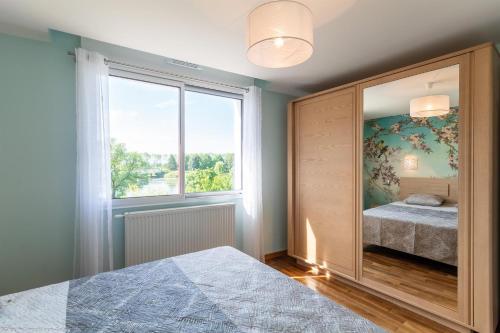 ein Schlafzimmer mit einem großen Fenster und einem Bett mit einem Spiegel in der Unterkunft Les Bords de Saône in Rigny