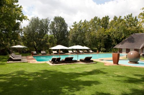 - une piscine avec des chaises et des parasols dans la cour dans l'établissement Valley Lodge & Spa, à Magaliesburg