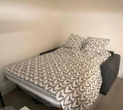 a bed with black and white sheets and pillows at ENGHIEN-LES-BAINS : studio au coeur du centre ville in Enghien-les-Bains