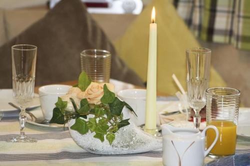 a table with a candle and a vase with flowers at Cafe Wastelbauerhof - Urlaub auf dem Bauernhof in Bernau am Chiemsee