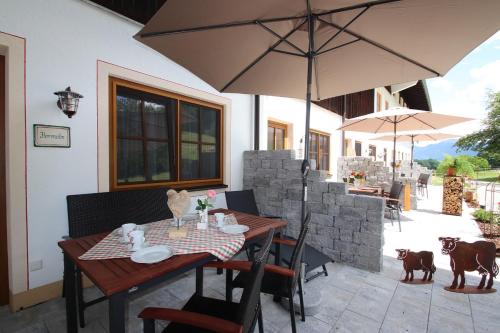 a wooden table with chairs and an umbrella on a patio at Cafe Wastelbauerhof - Urlaub auf dem Bauernhof in Bernau am Chiemsee