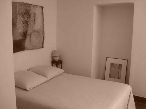 Conilhac-CorbièresにあるLa Maison Du Ruisseauの白いベッドと壁に絵画が飾られたベッドルーム1室