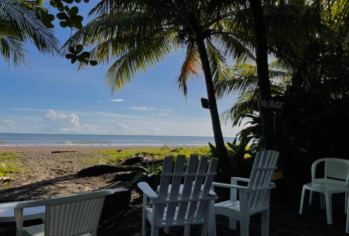 two chairs and a table on a beach at Hotel El Icaco Tortuguero in Tortuguero