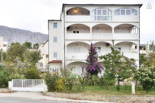 um grande edifício branco com flores em frente em Apartment in Duce with sea view, terrace, air conditioning, WiFi 5063-1 em Duće
