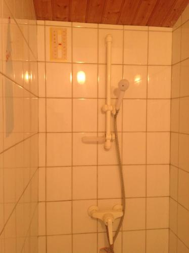 La salle de bains est pourvue d'une douche et d'un mur carrelé blanc. dans l'établissement Ferme Auberge L'Ile Sauvage, à Bouin