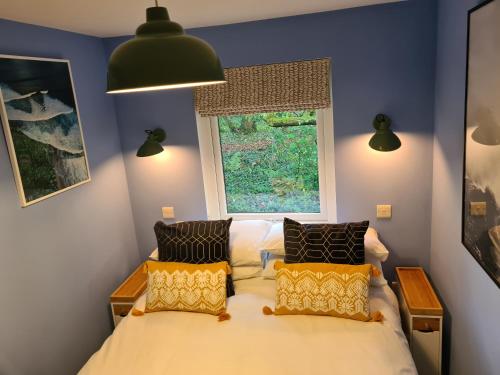 a bedroom with a bed with two pillows and a window at Pebble Cottage in Uny Lelant