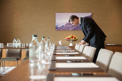 a man in a suit standing over a long table at AlpenGold Hotel Davos in Davos