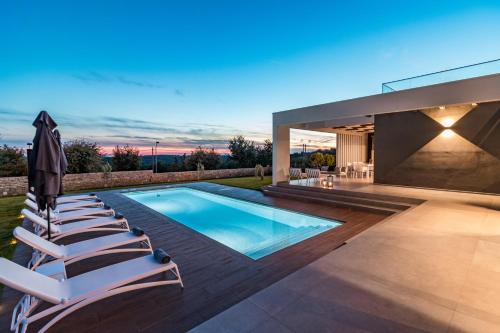 a swimming pool with lounge chairs next to a house at Villa Sabina in Višnjan