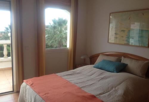 a bedroom with a bed and a window with a palm tree at Lovely villa in family resort in Miami Platja