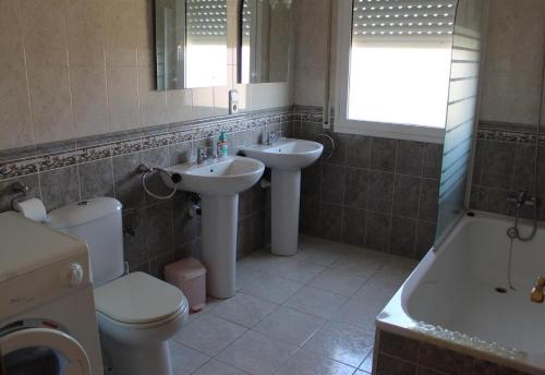 a bathroom with two sinks and a toilet and a tub at Lovely villa in family resort in Miami Platja