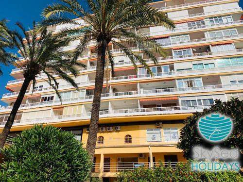a hotel with palm trees in front of a building at SkySea Holidays LA CARIHUELA in Torremolinos